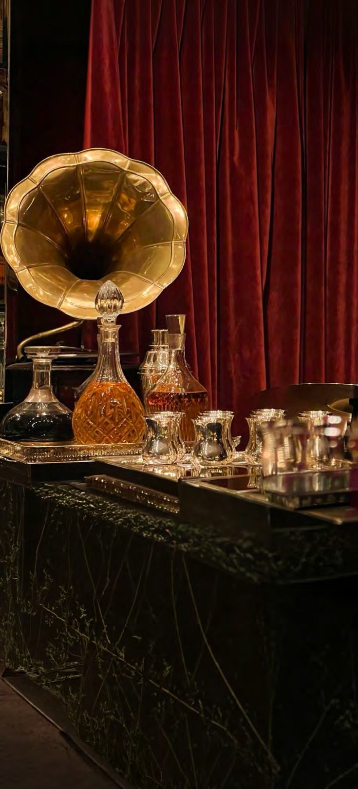 A brass gramophone horn beside crystal decanters of whiskey